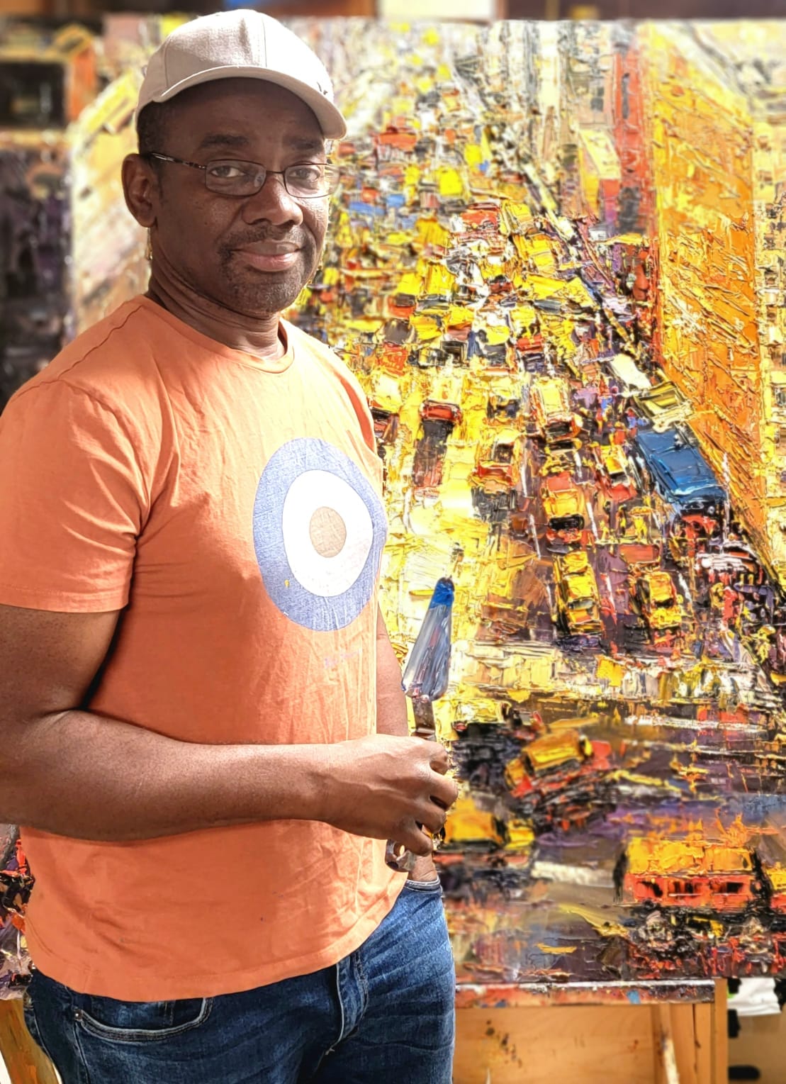 Artist standing next to a colorful, abstract painting with a palette knife in hand.