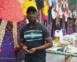 An artist standing in front of a colorful Commission painting in Washington DC.