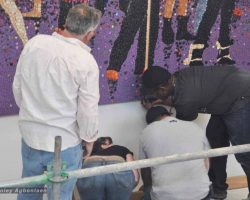 A group of people working to stall a mosaic painting in a school in Washington DC.