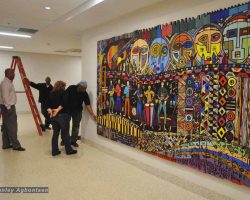 A group of people looking at a large wood panel painting in a school in Washington DC.